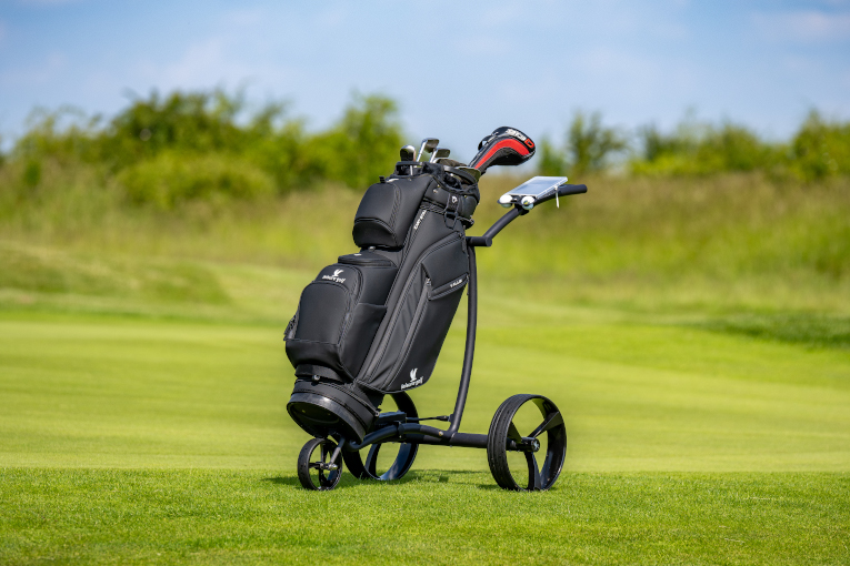 Elektro-Golf-Trolley mit Schlägern bestückt steht auf einem Golfplatz