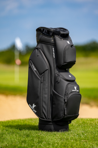 Eine schwarze Golfbag steht stehend auf einem Golfplatz