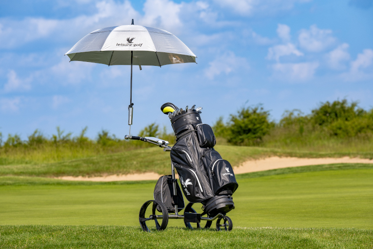 Golfschirm angebracht an einem Golf-Trolley, der auf einer Golfwiese steht